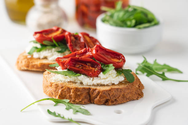 istock Bruschetta with sunny dried tomatoes and arugula.  White background, close-up view 1287201720