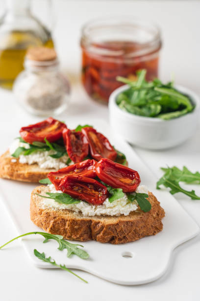 istock Bruschetta with sunny dried tomatoes and arugula.  White background, close-up view 1287201763