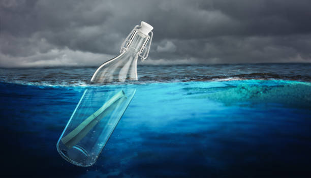 istock message rolled up in a glass bottle floating in the sea. 1287202912