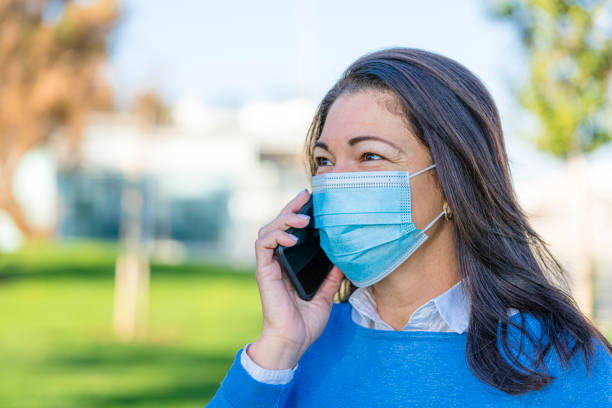 istock Woman on phone outdoors wearing protective face mask 1287204925