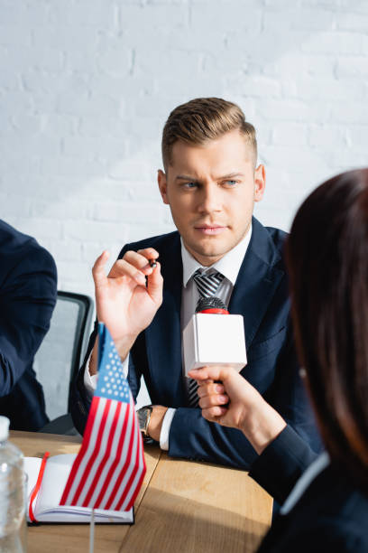 istock back view of journalist with microphone interviewing politician during press conference on  blurred foreground 1287206238