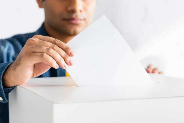 istock cropped view of indian man inserting ballot into polling booth 1287206240