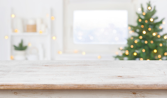 Espacio de mesa frente al alféizar de la ventana desenfocado con árbol de Navidad photo