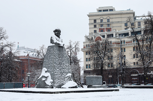 Moscow - Russia, November 23rd, 2020 - The first snow of the year arrived in Moscow and the Red Square is completely covered. Carl Marx Statue with snow.