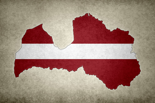 Grunge map of Latvia with its flag printed within its border on an old paper.