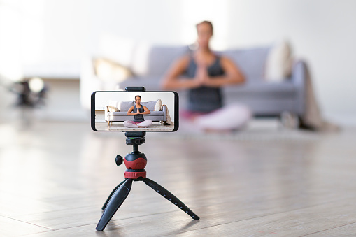 Yoga online to live streaming on a smartphone - fitness trainer teaches exercise so that the audience via the Internet. Focus on smartphone.