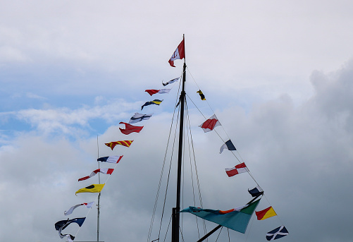Mast with signal flags against blue sky.