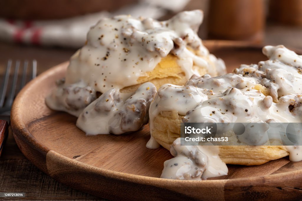 Biscuits and Creamy Sausage Gravy Closeup of biscuits and creamy sausage gravy on a wooden plate Biscuit - Quick Bread Stock Photo
