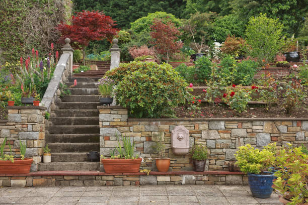 Natural stone steps and retaining wall, planter and garden border framing home entrance. Beautiful hardscape, colorful landscape design Natural stone steps and retaining wall, planter and garden border framing home entrance. Beautiful hardscape, colorful landscape design. hardscape photos stock pictures, royalty-free photos & images