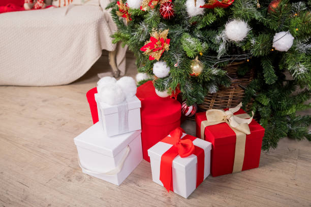 istock Christmas gift boxes and shopping package under Chrismas tree.New year present paper package. gift packages with ribbons.New year's gifts stand under Christmas tree with toys. Background for website. 1287214555