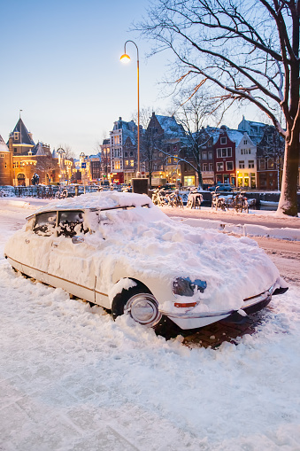Classic french car covered with snow on a winter day during sunset in Amsterdam, The Netherlands