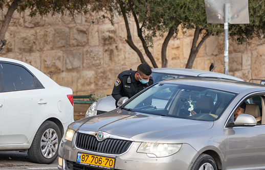 Jerusalem, Israel, November 14, 2020 : Israeli police officer checks documents of a driver of a private car near a Dung Gate in the old city of Jerusalem in Israel