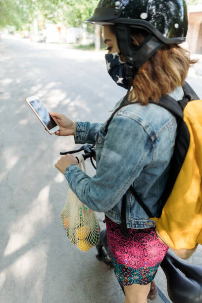 istock Young woman standing outside and looking at phone 1287218399