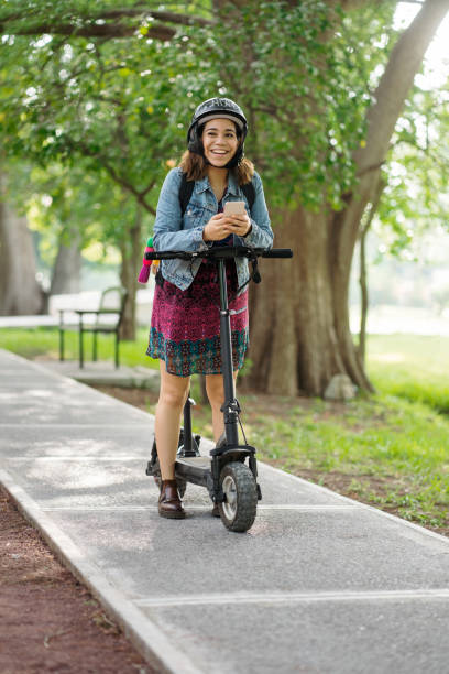 istock Latin woman standing with motorized scooter and smiling 1287218468
