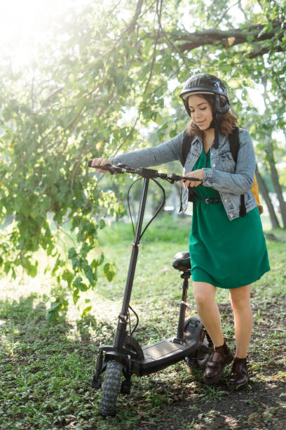istock Young woman standing outside with electric scooter 1287218548