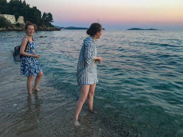 Two sisters together at the beach, standing in the sea, skimming stones Two siblings, aged 16 and 17 together at the beach of Cavtat, standing in the water while skimming stones in the sea. cavtat photos stock pictures, royalty-free photos & images