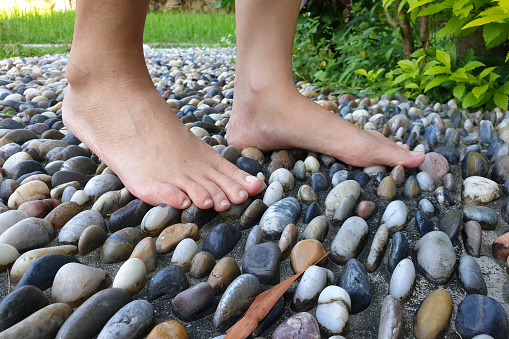 Cropped image woman feet walking on cobble pavement, healthy lifestyle, reflexology
