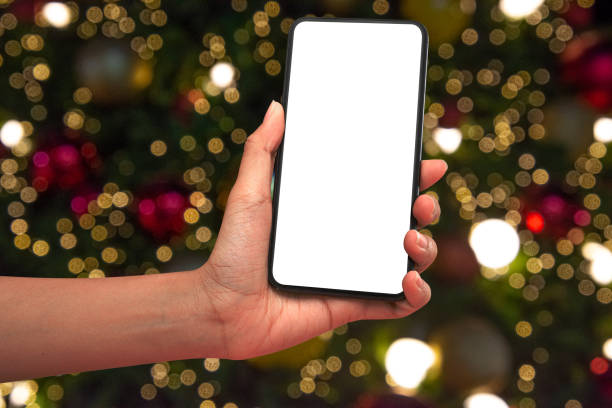 istock Close up hand holding phone isolated on white background with Illuminated  blurred bokeh of  Christmas tree decoration with  hanging lights ball. 1287224982
