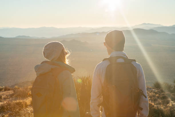 istock Couple contemplate landscape from mountain top at sunrise 1287228607