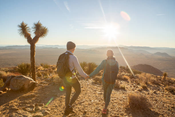 istock Hikers reach mountain top at sunrise, woman pulls man with hand 1287228869