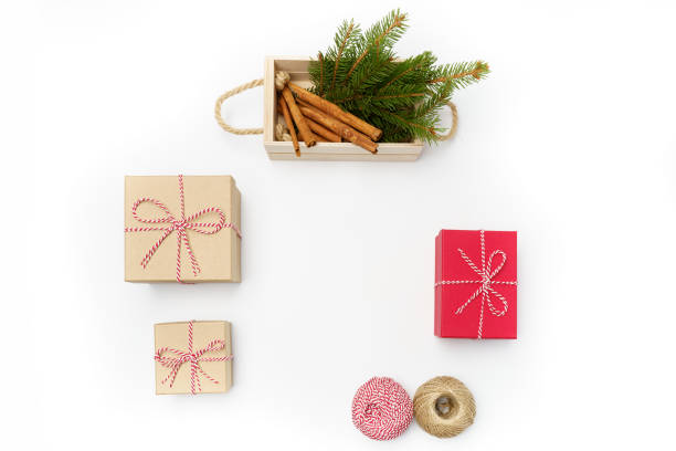 istock Flat lay craft boxes with natural rope and wooden box with cinnamon sticks and pine tree branches on white background. 1287229369