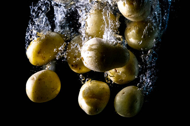 istock Large amount of potatoes falling into the water. 1287230475