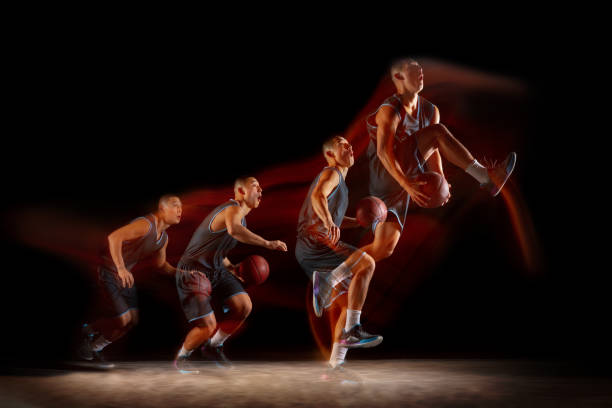Young east asian basketball player in action and jump in mixed strobe light over dark studio background. Concept of sport, movement, energy and dynamic, healthy lifestyle. Flying. Young east asian basketball player in action and motion jumping in mixed strobe light over dark studio background. Concept of sport, movement, energy and dynamic, healthy lifestyle. match lighting equipment photos stock pictures, royalty-free photos & images