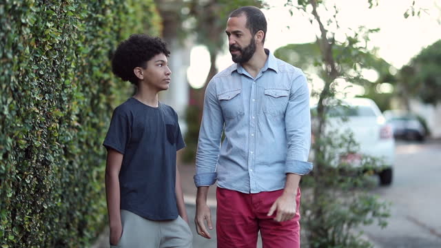 Candid father giving advice to son outside walking in street