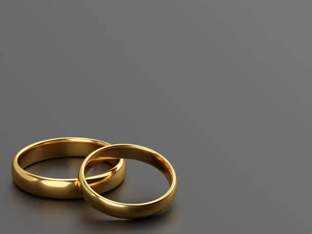 Two wedding gold rings lie next to each other on grey background. 3d rendering