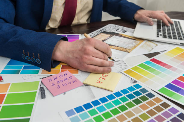 istock Architects hands drawing of modern apartaments with colour sample and laptop on creative desk, office. Man choosing colors for room decoration. 1287239208