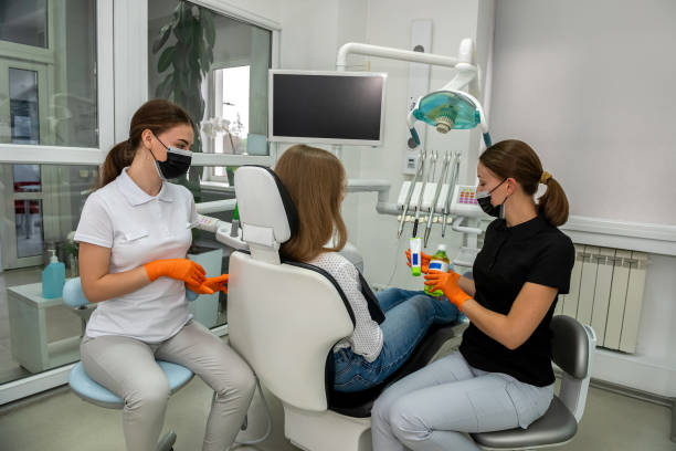 여성 치과 의사와 젊은 조수 는 치과 외투에서 환자 치아를 수리하고 - ambulant patient 뉴스 사진 이미지