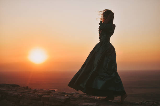 Happy woman dancing and holding scarf while enjoys spending time at sunset.