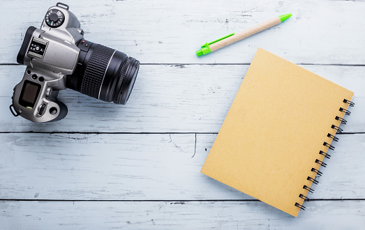 Recycle notebook and old camera on blue wooden background