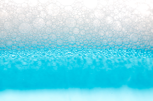Detail of soap bubbles in clear blue liquid background