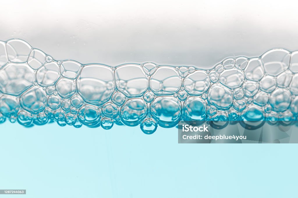 Detail of soap bubbles in clear blue liquid background Disinfection Stock Photo