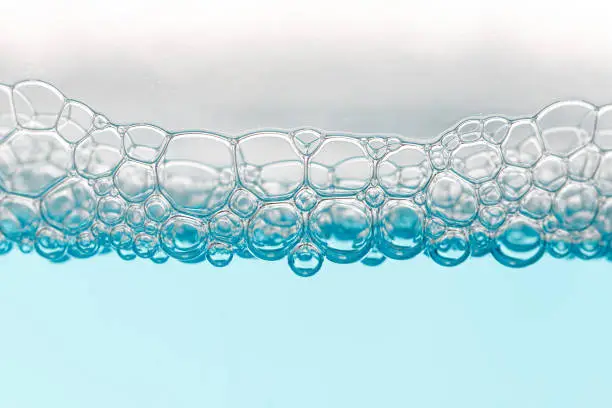 Detail of soap bubbles in clear blue liquid background