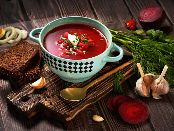Ukrainian and Russian national red borsch with sour cream and herbs. Bowl of red beetroot soup on dark rustic background