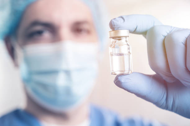 istock Doctor man holding a syringe with Coronavirus vaccine 1287245009