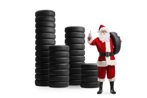 Full length portrait of santa claus with piles of car tires isolated on white background