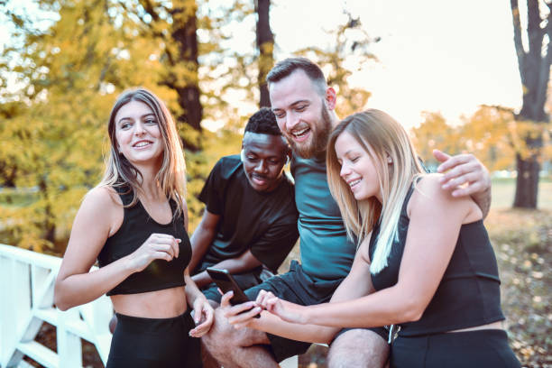 istock Multi Ethnic Athletes Exploring Social Media On Smartphone While Relaxing In Park 1287246115