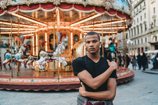Young adult man against a merry go round carousel in Florence