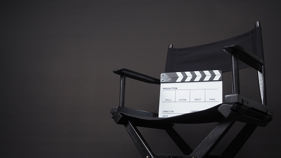 Clapperboard or clap board or movie slate with black director chair use in video production ,film, cinema industry on black background.