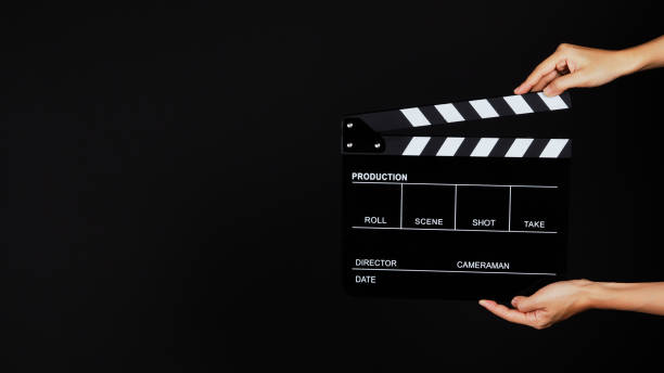 istock Hand is holding Black clapperboard or movie slate on black background. 1287249131