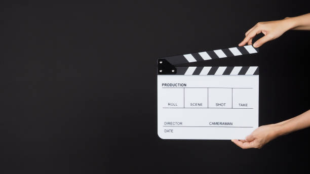 istock Hand is holding white clapper board or movie slate on black background. 1287249158