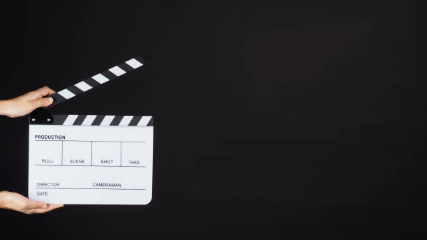 istock Hand is holding white clapper board or movie slate on black background. 1287249255