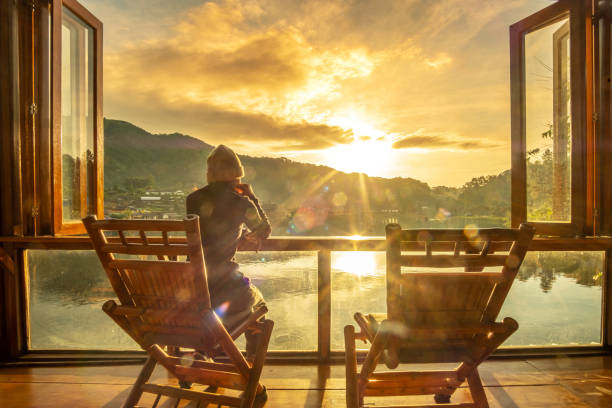 joven sola viendo la vista al lago en la cafetería en el amanecer de la mañana, ban rak pueblo tailandés, provincia de mae hong son, tailandia. concepto de viaje - tourism panoramas winter travel locations fotografías e imágenes de stock