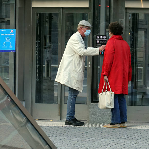 Corona / Covid-19 Lockdown in Copenhagen, Denmark. Old couple with facemask to protect from viruses, waitng for the elevator at a metrostation on a sunny day in central Copenhagen, Denmark. After the Covid 19 pandemic, people wearing facemask is getting more and more common. town hall square copenhagen stock pictures, royalty-free photos & images