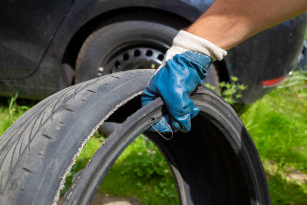 copcept of dangerous drive.  the hand of the master in a blue glove holds the torn tire with wire. close up. on the background black car in blur stock photo