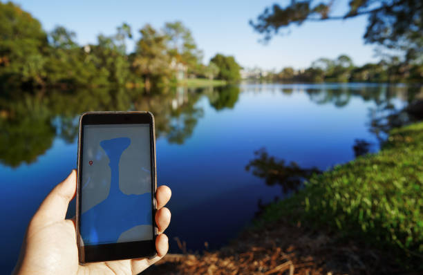 Man using mobile map app next to the lake stock photo