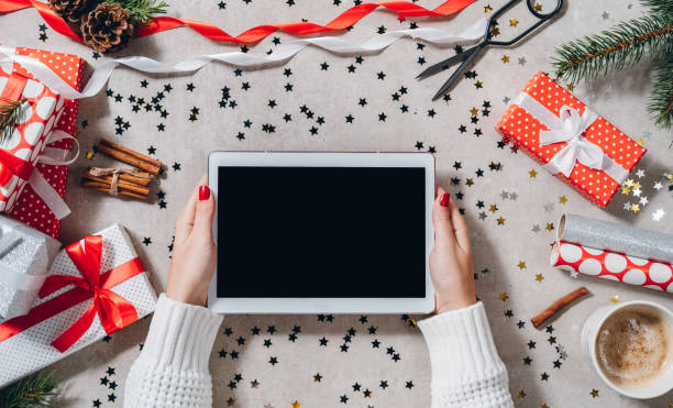 istock Woman hands holding blank screen tablet on Christmas decorated table 1287252817